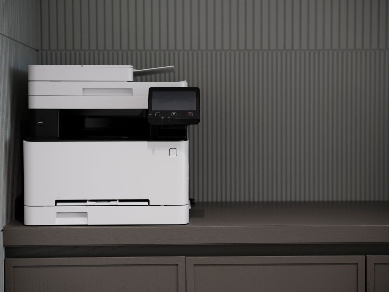 A sleek, modern printer situated on a minimalist office desk with a textured background.