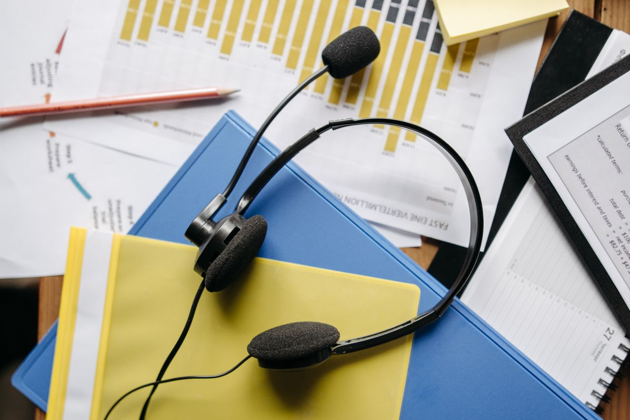 Crafting Captivating Headlines: Your awesome post title goes here Close-up of an office desk with headset, charts, and documents showcasing customer service support.